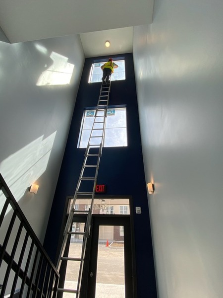 Nice and Clean Solutions worker on high ladder cleaning window